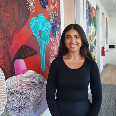 Young woman smiling in front of colorful abstract wall art.