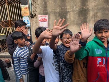 Group of boys raising their hands and smiling.