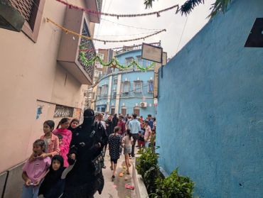 A crowded narrow alley with people walking.
