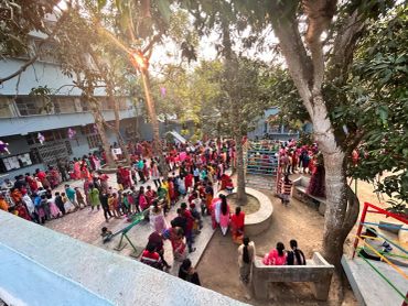 Children stand in long lines outdoors at a school.