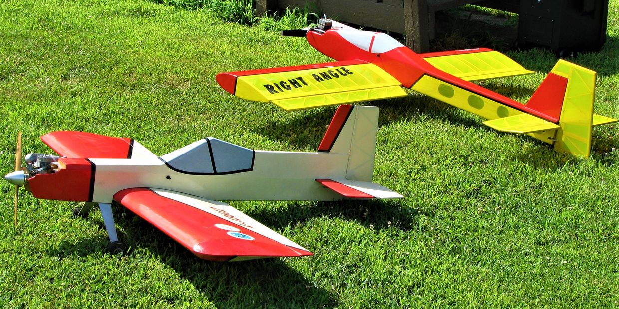 Two colorful remote-controlled model airplanes on grass.