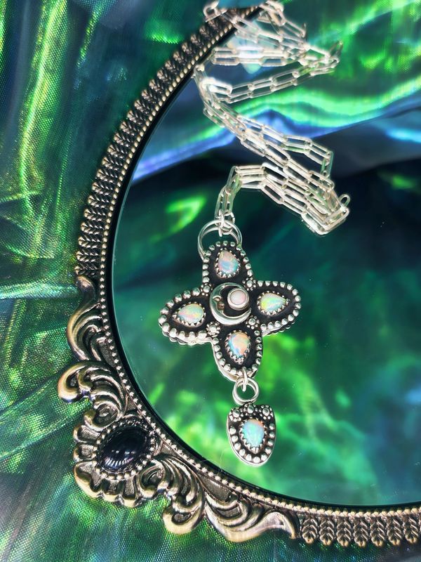 Silver necklace with opal stones on a decorative mirror.