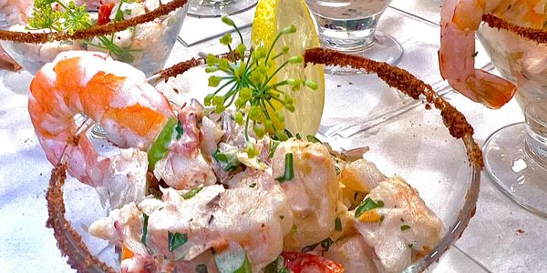 Shrimp cocktail served in a glass with creamy sauce and a lemon wedge.