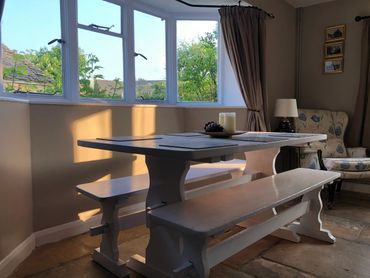 Dining table in the bay window. Seating for 6 on benches, highchair or additional chairs available.