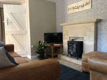 Cosy livingroom area with stone fireplace, electric stove.