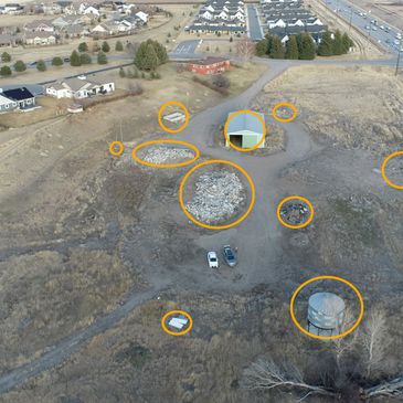 Aerial view of a field with scattered debris and buildings.