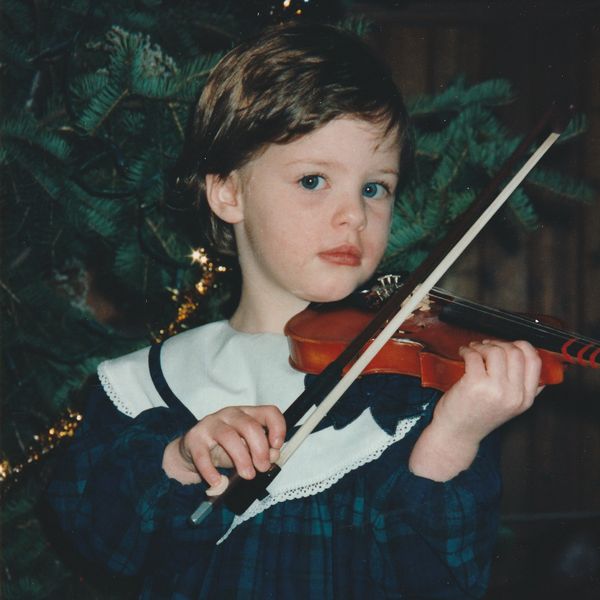 Young child playing violin with focus and care.