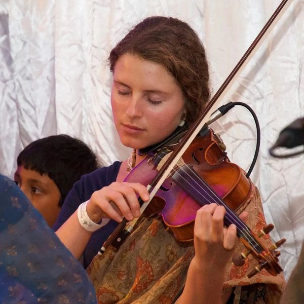A woman playing the violin with eyes closed, immersed in music.