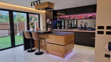 Modern kitchen with island, bar stools, and ambient lighting.