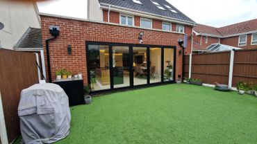 Modern backyard with artificial grass and large glass doors.