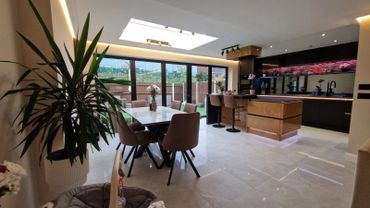 Modern kitchen and dining area with large windows and sleek design.