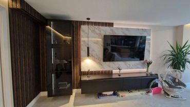 Modern living room with TV, sleek wooden paneling, and a baby rocker.