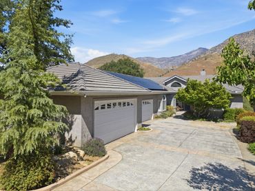 Modern house with solar panels on the roof and a spacious driveway.