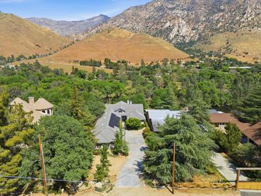 A suburban house surrounded by trees with mountains in the background.