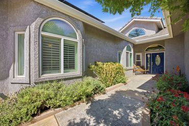 Front entrance of a house with arched windows and garden pathway.