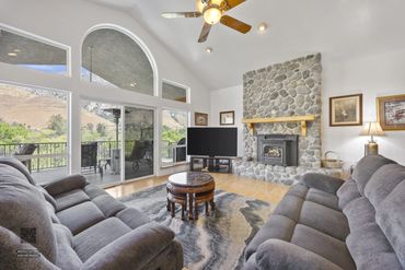 Cozy living room with stone fireplace and large windows overlooking mountains.