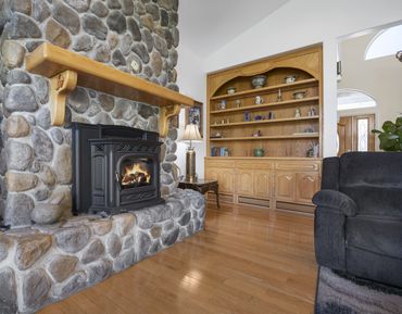Cozy living room with stone fireplace and wooden shelves filled with decor.