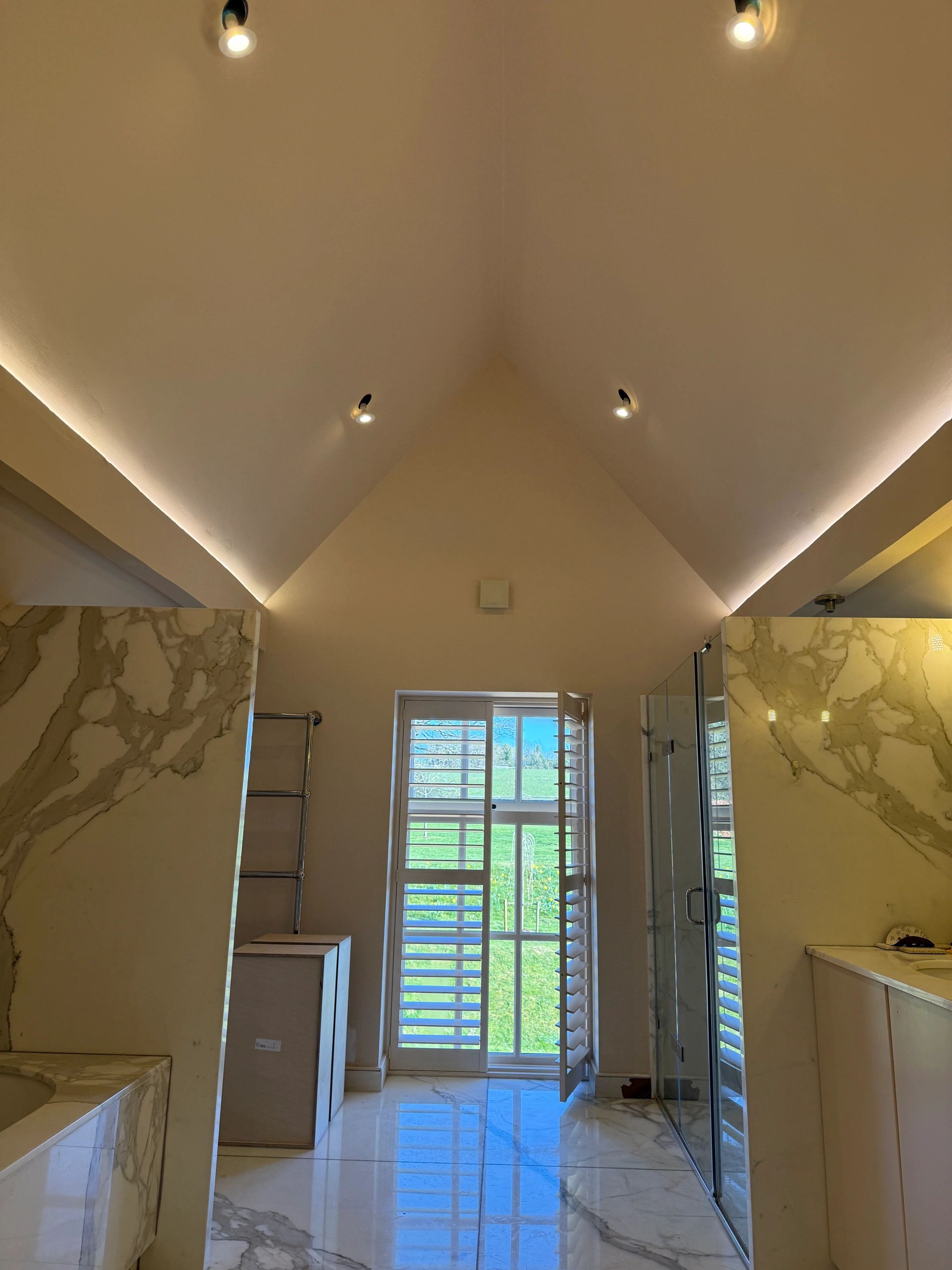 Luxurious bathroom with marble finishes and a window overlooking a green landscape.