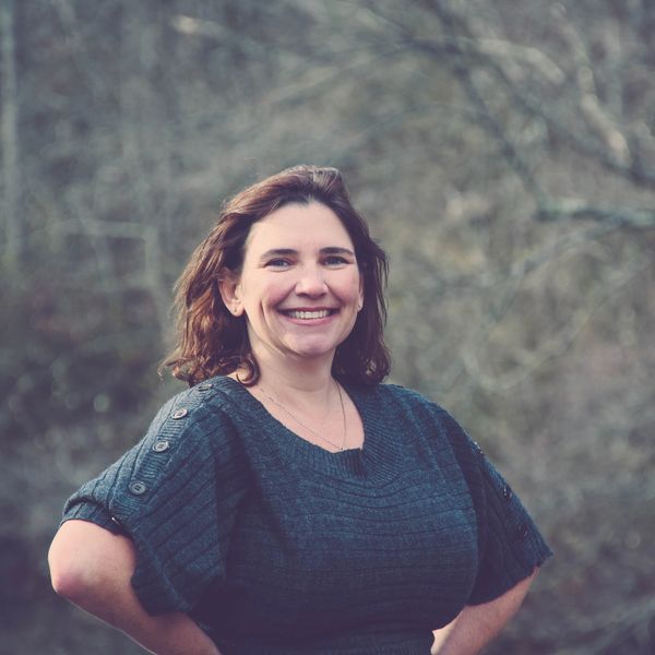Smiling woman outdoors with hands on hips.