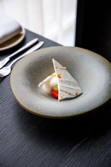 A delicate dessert with a meringue topping on a gray plate.
