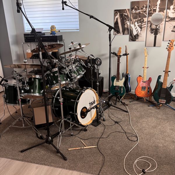 A music room with a drum set, guitars, and a Minion figurine.