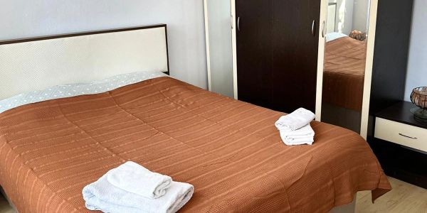 Neatly made bed with brown cover and folded white towels.