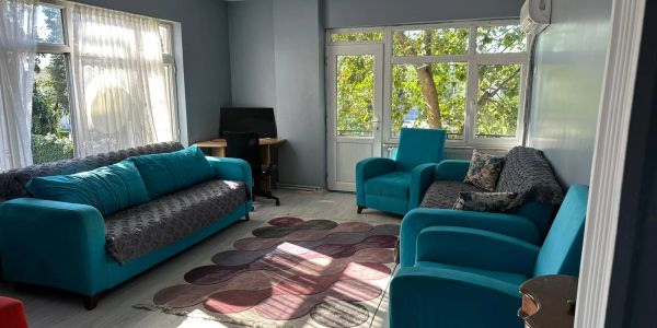 Cozy living room with teal sofas and natural light from large windows.