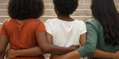 Three women linking arms, showing unity and support.