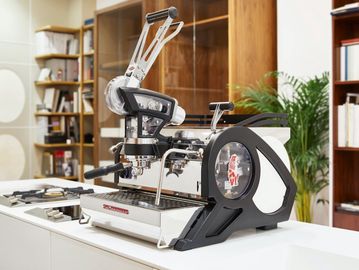 Modern espresso machine on a kitchen counter with bookshelves and plants.