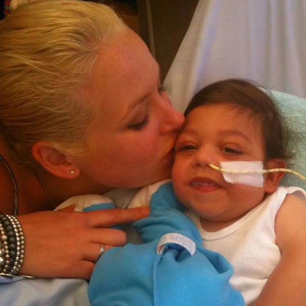 A mother kissing her baby son. Baby has a feeding tube in his nose