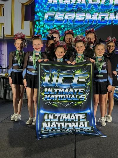 Young cheerleaders holding a championship banner at a national awards ceremony.