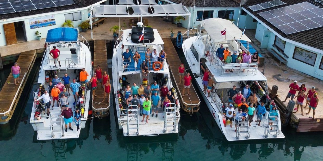 Groups of people posing on three docked boats at a marina.