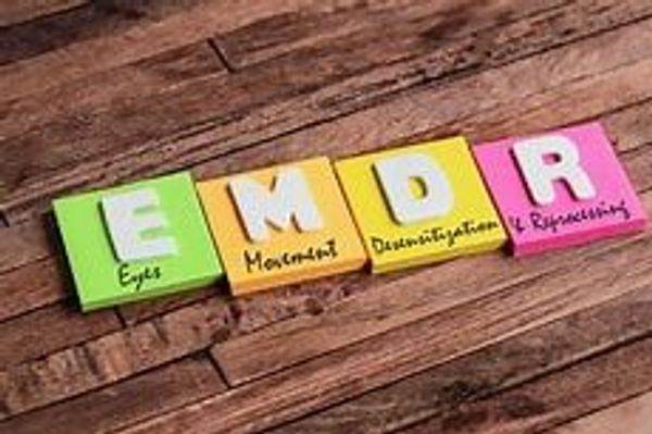 Colorful blocks spell EMDR with corresponding words on a wooden surface.