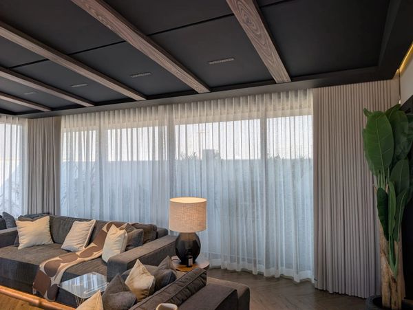 Cozy living room with large windows, sheer curtains, and modern furniture.