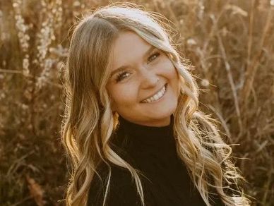 Young woman smiling in a natural outdoor setting.