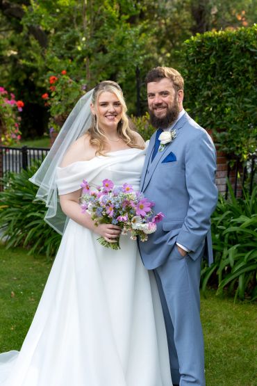 Bride and groom smiling in a garden.