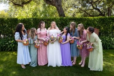Bride with bridesmaids holding bouquets outdoors.