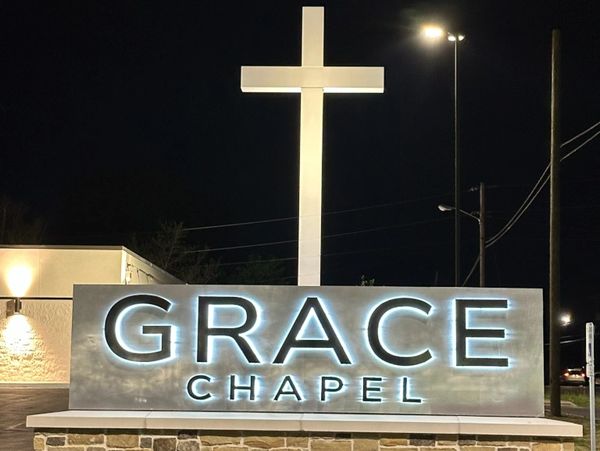 Illuminated Grace Chapel sign with a glowing cross at night.