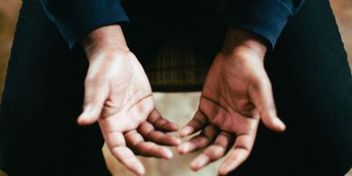 Open hands resting on lap, palms up, in a relaxed posture.