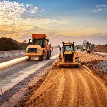Heavy machinery working on road construction during sunset.