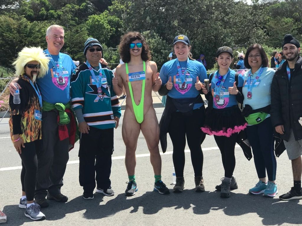 Group of runners posing after a race, one in a bright green mankini.