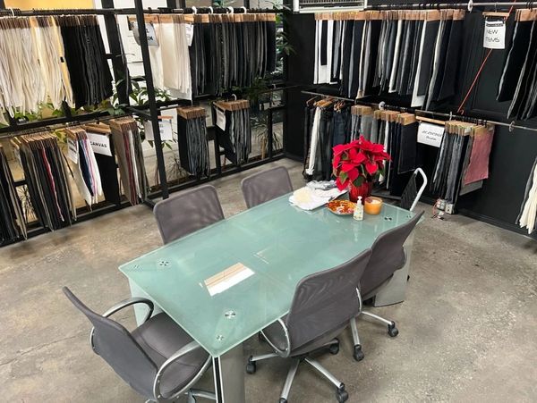 Showroom. Glass table with chairs on concrete floors. Denim fabric selections hang across the walls.