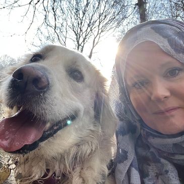 A woman looking happy next to a friendly dog in a woodland area