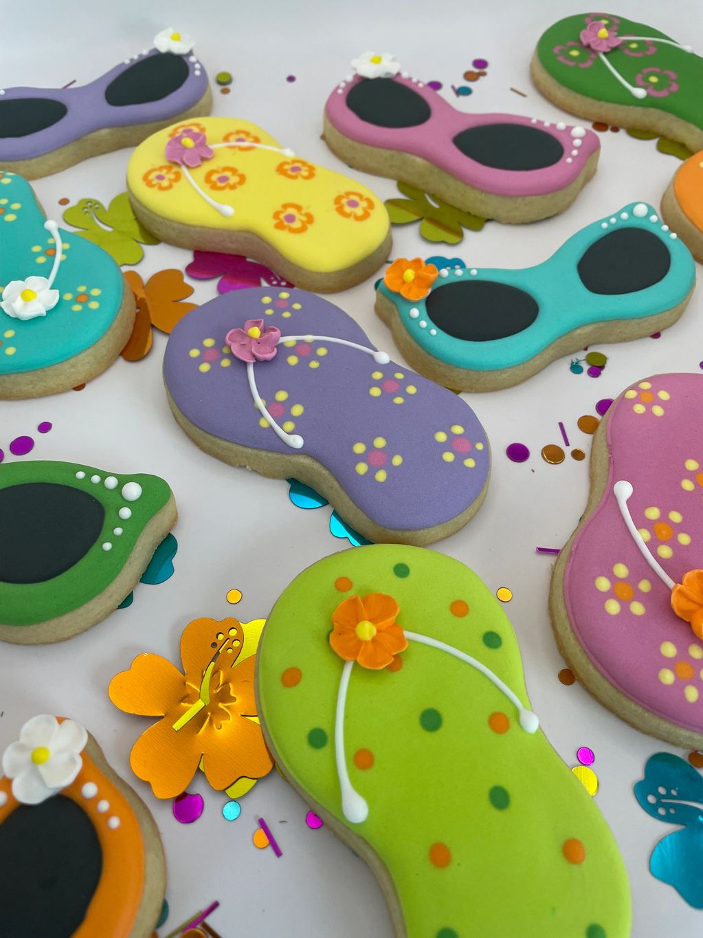 Colorful flip-flop shaped cookies with floral decorations.