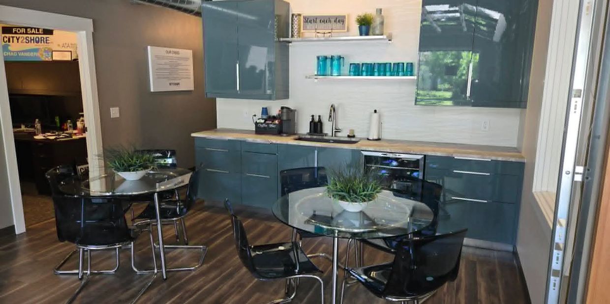 Modern kitchen with glass tables, blue cabinets, and wooden flooring.