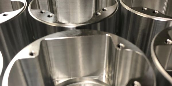 Close-up of shiny, cylindrical metal parts with drilled holes.