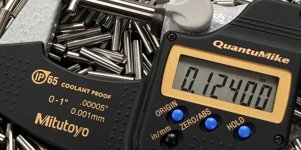 Digital micrometer measuring a small metal rod with precision.