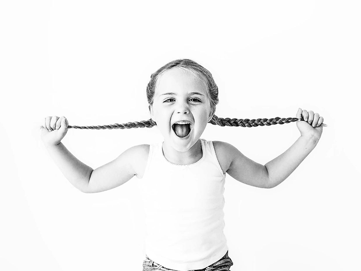 Happy girl pulling her braided hair.