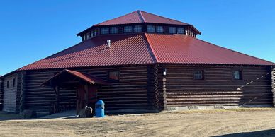 Large octagonal wooden building under clear sky.