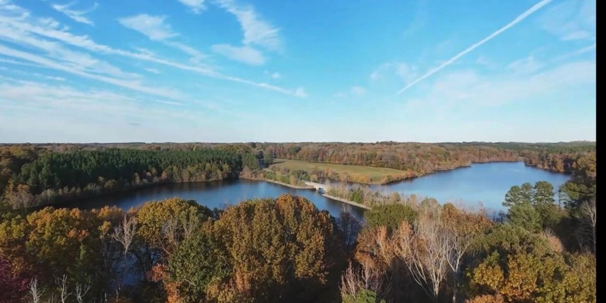 A serene lake surrounded by autumn trees under a clear blue sky.